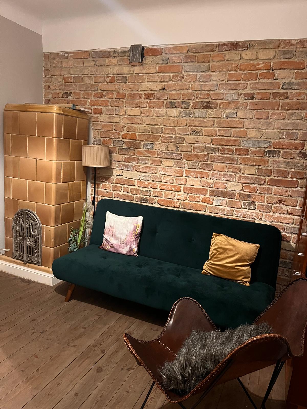Zielona sofa i ceglana ściana w gabinecie